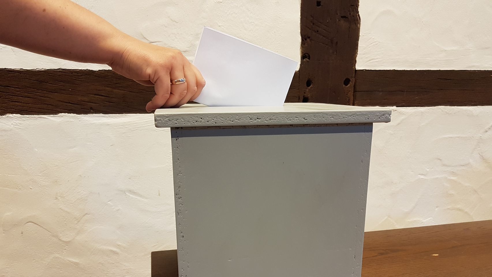 Wahlurne Symbolbild Wahlurne in die ein Zettel geworfen wird.