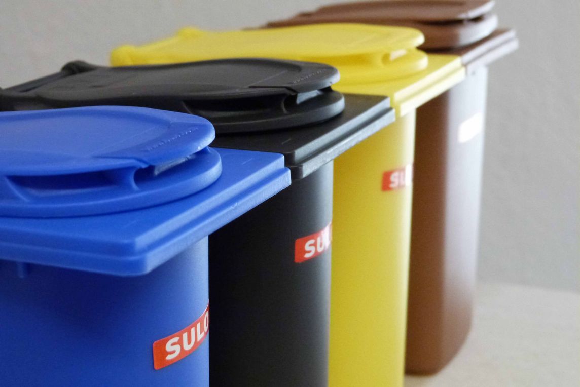 Symbolbild Müllabfallbehälter in Blau, Schwarz, Gelb und Braun